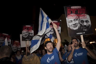 Israelis hold up banners during a demonstration in Tel Aviv against the emerging natural gas deal. Hebrew on the sign reads, 'Netanyahu and Deri stink of corruption,' referring to Israeli Prime Minister Benjamin Netanyahu and Economy and Commerce Minister Aryeh Deri. (AP Photo/Dan Balilty)