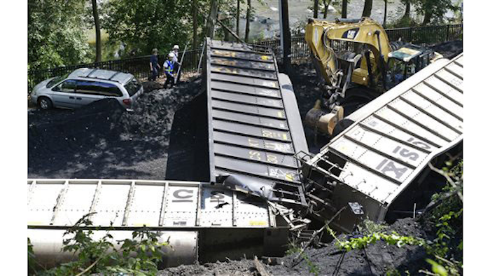 In this Tuesday, Aug. 21, 2012, file photo, officials, top left, inspect part of a CSX freight train that derailed alongside a parking lot overnight in Ellicott City, Md. A little-known truth about North American railroads: No rules govern when rail becomes too worn down. Since 2000, U.S. officials blamed rail wear as the direct cause of 111 derailments causing $11 million in damage. (AP Photo/Patrick Semansky, File)