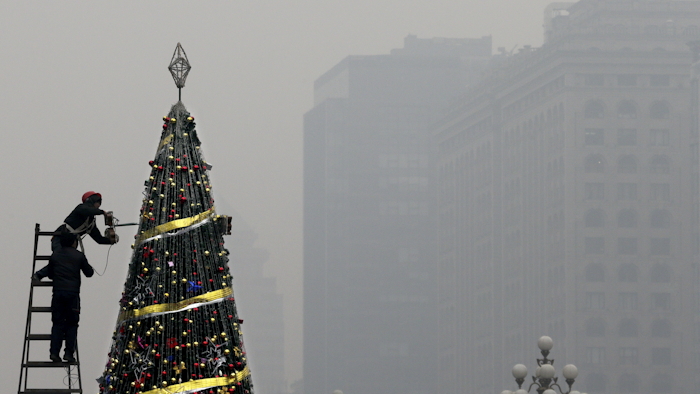 Workers install a Christmas tree on display outside a shopping mall in a heavy pollution haze in Beijing. (AP Photo/Andy Wong)