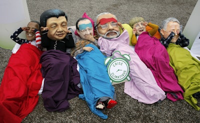 Oxfam activists wear masks as they stage a protest during the COP21. (AP Photo/Christophe Ena)