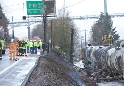 Firefighters work at the scene after a semitrailer truck crashed into railroad cars causing a fire near the St. Johns Bridge in Portland, Ore., Sunday, Dec. 13, 2015. (AP Photo/Craig Mitchelldyer)