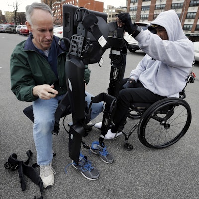 ReWalk Robotics service engineer Tom Coulter prepares a ReWalk device to allow paralyzed Army veteran Gene Laureano to walk Wednesday, Dec. 16, 2015, in Bronx, N.Y. (AP Photo/Mel Evans)