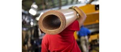 In this Friday, Sept. 18, 2015, photo, a worker carries a roll of sub flooring to be installed in a school bus on an assembly line at Blue Bird Corporation's manufacturing facility, in Fort Valley, Ga. The Institute for Supply Management, a trade group of purchasing managers, issues its index of manufacturing activity for December, on Monday, Jan. 4, 2016. (AP Photo/David Goldman)