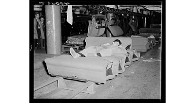 A striker sleeps on an assembly line of auto seats while off guard duty. (Photo by Sheldon Dick, courtesy of Wikimedia Commons)
