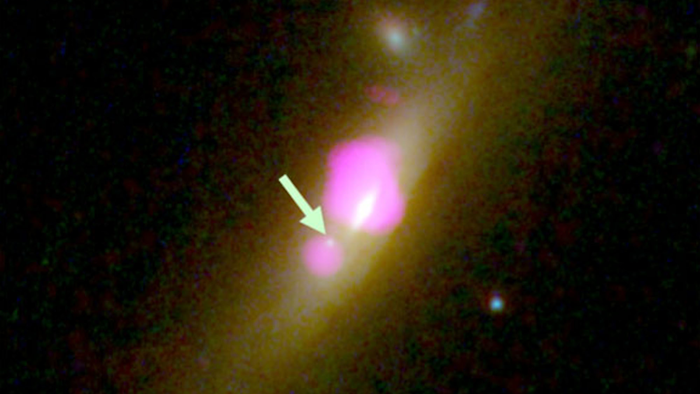This image provided by CU-Boulder shows the galaxy SDSS J1126+2944 taken with the Hubble Space Telescope and the Chandra X-ray Observatory, with an arrow placed by the source pointing to a black hole that lost most of its stars. (NASA/CU-Boulder via AP)