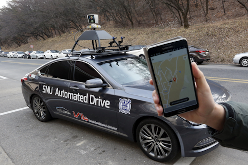A researcher fromm the Intelligent Vehicle IT Research Center at Seoul National University shows the smartphone application for the driverless car called Snuber with a fixture on its roof with devices that scan road conditions at Seoul National University’s campus in Seoul, South Korea. (AP Photo/Lee Jin-man)