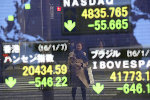 A woman is reflected on an electronic stock board of a securities firm in Tokyo. (AP Photo/Eugene Hoshiko)