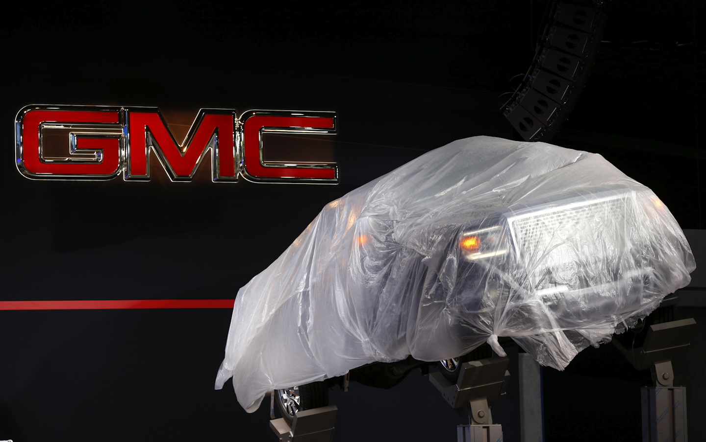 A GMC pickup truck is shown elevated in plastic in preparation for the upcoming North American International Auto Show in Detroit. (AP Photo/Paul Sancya)