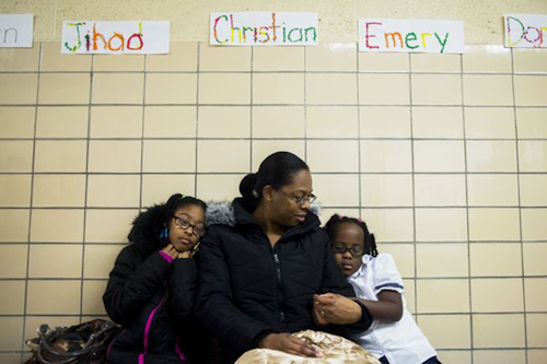 LaShanti Redmond, 10, left, and her sister Asharra Smith, 6, hold onto their mother Charlene Mitchell, all of Flint, for comfort as they wait to get their blood tested for lead levels in Flint, Mich., Tuesday, Jan. 12, 2016. (Jake May/The Flint Journal-MLive.com via AP)