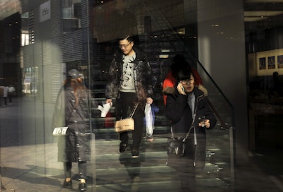 A man with his purchased goods walks down staircase as he prepares to leave an Apple Store in Beijing. (AP Photo/Andy Wong)