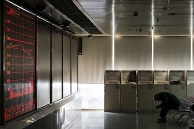 A man sits near an electronic board displaying stock prices at a brokerage house in Beijing, Tuesday, Jan. 26, 2016. Asian stock markets sank Tuesday, led by a plunge in the Shanghai index, after a renewed slump in the price of oil kept investors on edge about the global economy. (AP Photo/Andy Wong)