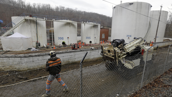 This Monday Jan. 13, 2014 file photo shows a worker moves a drilling machine around storage tanks at Freedom Industries storage facility in Charleston, W.Va. Two years after thousands of gallons of a coal-cleaning agent leaked into the drinking water supply of 300,000 West Virginians, the sentencings of six officials at a chemical distributor in February brings a closure to criminal cases in the spill. (AP Photo/Steve Helber)