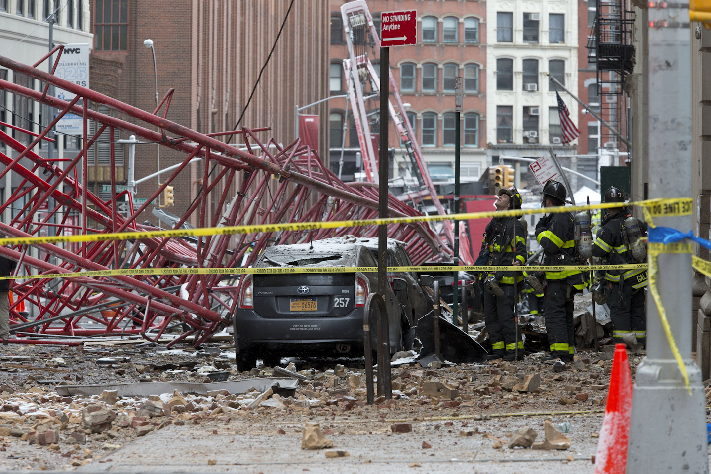 Firefighters work at the scene of a crane collapse in lower Manhattan, Friday, Feb. 5, 2016 in New York. The crane landed across an intersection and stretched much of a block in the Tribeca neighborhood, about 10 blocks north of the World Trade Center. (AP Photo/Mary Altaffer)