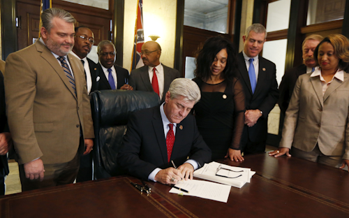 Surrounded by lawmakers of both chambers, Mississippi Gov. Phil Bryant signs HB1, a special session economic package of hundreds of millions of dollars of state money and incentives for a tire plant in western Hinds County and a shipyard in Gulfport, Monday, Feb. 8, 2016 at the Capitol in Jackson, Miss. (AP Photo/Rogelio V. Solis)