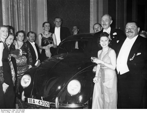 German Press Ball 1939. Dr. Ferdinand Porsche presents the Volkswagen tombola prize to Mrs. Elsa Ellinghausen, the lucky winner. (Image Credit: Wikimedia Commons/Bundesarchiv, Bild)