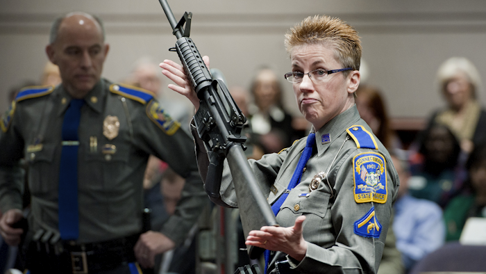 In this Jan. 28, 2013, file photo, firearms training unit Detective Barbara J. Mattson, of the Connecticut State Police, holds up a Bushmaster AR-15 rifle, the same make and model of gun used by Adam Lanza in the Sandy Hook School shooting, during a hearing of a legislative subcommittee, at the Legislative Office Building in Hartford, Conn. Lawyers for the company that made the rifle Lanza used at Sandy Hook Elementary School in 2012 are expected to ask a Connecticut judge Monday, Feb. 22, 2016, to dismiss a wrongful death lawsuit filed by families of some of the massacre victims. Freedom Group, the Madison, North Carolina parent company of AR-15 maker Bushmaster Firearms, says it’s protected by a 2005 federal law that shields gun manufacturers from most lawsuits over criminal use of their products. (AP Photo/Jessica Hill, File)