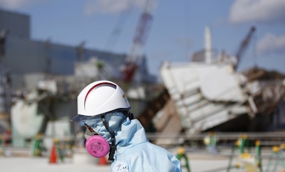 A Tokyo Electric Power Co. (TEPCO) employee, wearing a protective suit and a mask, walks in front of the No. 1 reactor building at the tsunami-crippled Fukushima Dai-ichi nuclear power plant in Okuma, Fukushima Prefecture, northeastern Japan, Wednesday, Feb. 10, 2016. In one month, Japan is marking the fifth anniversary of a devastating earthquake and tsunami that hit on March 11, 2011 and left nearly 19,000 people dead or missing, turned coastal communities into wasteland and triggered a nuclear crisis. (Toru Hanai/Pool Photo via AP)