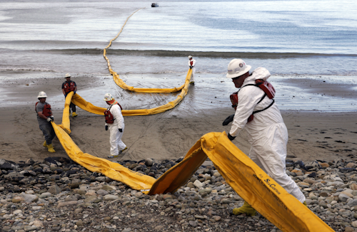In this May 21, 2015, file photo, workers prepare an oil containment boom at Refugio State Beach, north of Goleta, Calif., two days after a ruptured pipeline created the largest coastal oil spill in California in 25 years. (AP Photo/Jae C. Hong, File)