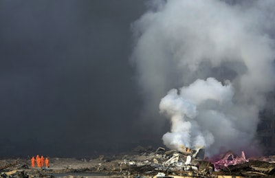 Firefighters in protective gear watch as smoke continues to billow out after an explosion at a warehouse in northeastern China's Tianjin municipality. (AP Photo/Ng Han Guan, File)