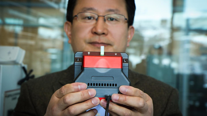 University of Utah materials science and engineering professor Ling Zang holds up a prototype handheld detector his company is producing that can sense explosive materials and toxic gases. His research team developed a new material for the detector that can sense alkane fuel, a key ingredient in such combustibles as gasoline, airplane fuel and homemade bombs.