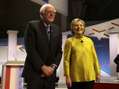 In this Feb. 11, 2016 file photo, Democratic presidential candidates Sen. Bernie Sanders, I-Vt, left, and Hillary Clinton smile as they take the stage before a Democratic presidential primary debate at the University of Wisconsin-Milwaukee, in Milwaukee. Clinton and Sanders are putting the global economy at the center of their pitch to Democrats, trading charges about who would best represent American workers as their presidential campaign shifts to a series of Rust Belt primaries. Clinton plans to deliver a policy address Friday, March 4, 2016, in Detroit outlining ways to remove economic barriers for families, giving her the opportunity to respond to Sanders, who has accused her of supporting trade deals that have had 'disastrous' consequences for workers. (AP Photo/Tom Lynn, File)