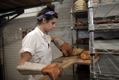 In this Friday, June 5, 2015, file photo, Sarah Hinkes places freshly baked bread onto a rack at Zak the Baker in Miami. On Tuesday, March 15, 2016, the Labor Department reports on U.S. producer price inflation in February. (AP Photo/Lynne Sladky, File)