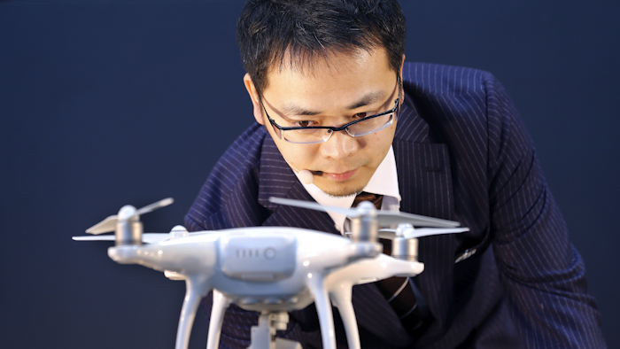 DJI Japan General Manager Allen Wu shows the major Chinese consumer-drone maker's Phantom 4 during the launch of the latest model in Tokyo, Thursday, March 3, 2016. The drone which has propellers, cameras, sensors and automatic tracking technology, zipped around and followed a stunt bicycle-rider, successfully dodging a signboard. (AP Photo/Shizuo Kambayashi)