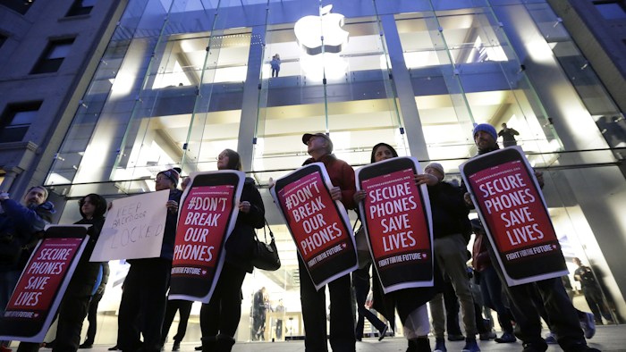 Protesters carry placards outside an Apple store in Boston. Tech companies, security experts and civil liberties groups are filing court briefs supporting Apple in its battle with the FBI. (AP Photo/Steven Senne, File)