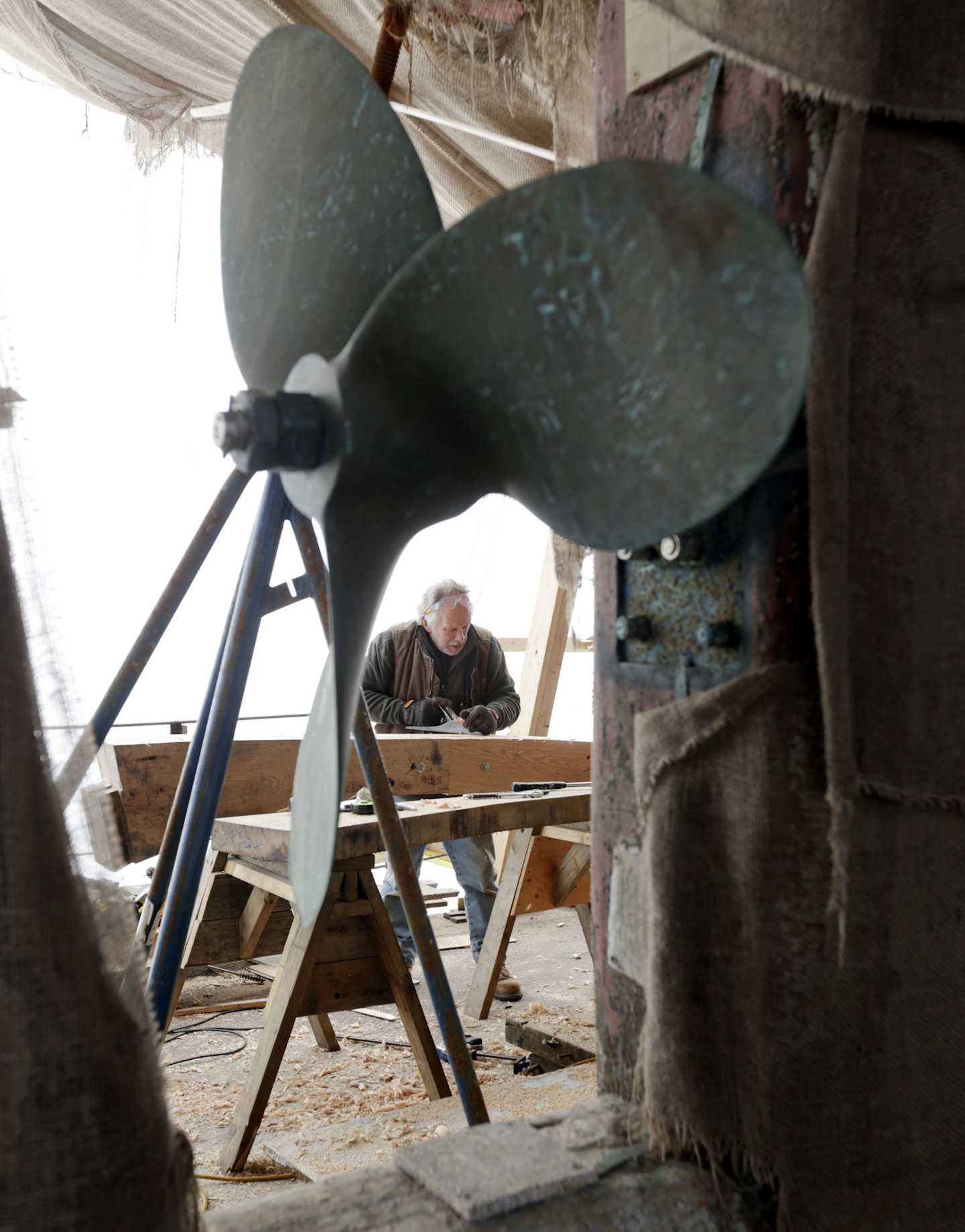 Peter Kricker planes wood while working on the restoration of the sloop Clearwater in Kingston, N.Y. (AP Photo/Mike Groll)