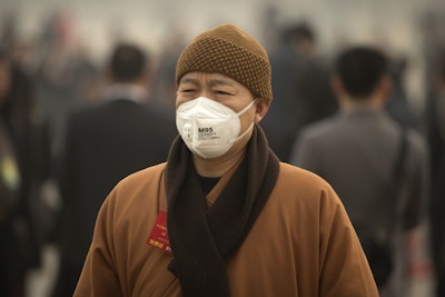 In this March 4, 2016 photo, a participant wearing a face mask arrives for a meeting ahead of the opening session of the National People's Congress (NPC) at the Great Hall of the People in Beijing. (AP Photo/Mark Schiefelbein)