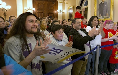 Supporters of a bill to raise California's minimum wage, celebrate outside the state Senate Chamber after the measure was approved by the Senate Thursday, March 31, 2016, in Sacramento, Calif. The bill, SB3, that will gradually raise California's minimum wage to a nation leading $15 an hour by 2022, was approved by both houses of the Legislature and sent to Gov. Jerry Brown who said he will sign it. (AP Photo/Rich Pedroncelli)