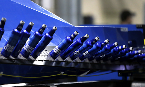 In this Friday, April 8, 2016, file photo, aluminum Bud Light bottles move along a conveyor at a plant manufacturing 16-ounce Budweiser and Bud Light aluminum bottles for Anheuser-Busch, in Arnold, Mo. On Friday, April 15, 2016, the Federal Reserve reports on U.S. industrial production for March. (AP Photo/Jeff Roberson, File)