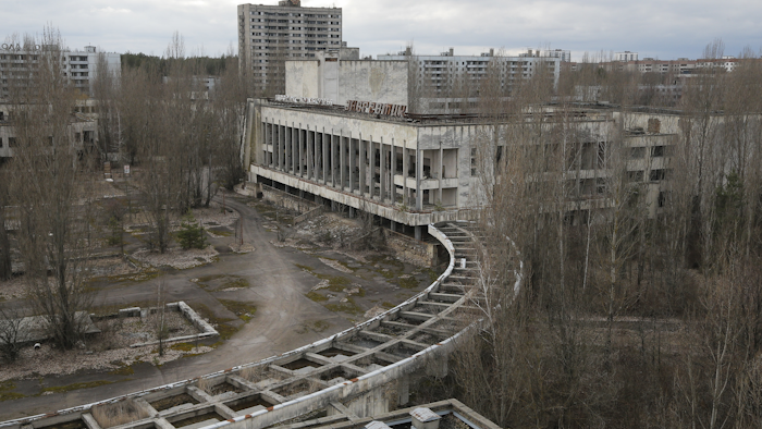 This photo taken Wednesday, March 23, 2016 shows abandoned apartment buildings in the town of Pripyat near Chernobyl, Ukraine, with a chimney, left, at the destroyed reactor and a gigantic arch-shape confinement to cover the remnants of the exploded reactor, in the back, at the Chernobyl nuclear power plant. Thirty years after the world’s worst nuclear accident, the Chernobyl nuclear power plant is surrounded by both a hushed desolation and clangorous activity, the sense of a ruined past and a difficult future. The Chernobyl nuclear power plant explosion was only about 60 miles from photographer Efrem Lukatsky's home, but he didn’t learn about it until the next morning from a neighbor. Only a few photographers were allowed to cover the destroyed reactor and desperate cleanup efforts, and all of them paid for it with their health. (AP Photo/Efrem Lukatsky)
