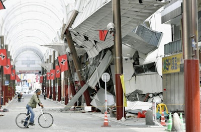 A cyclist looks at a shopping arcade destroyed by an earthquake in Kumamoto city, southern Japan. The powerful earthquake struck southwestern Japan early Saturday, barely 24 hours after a smaller quake hit the same region. (Kyodo News via AP)