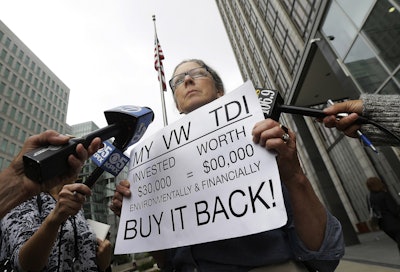 Joyce Ertel Hulbert, owner of a 2015 Volkswagen Golf TDI, holds a sign while interviewed outside of the Phillip Burton Federal Building in San Francisco, Thursday, April 21. (AP Photo/Jeff Chiu)