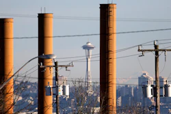 In this Feb. 25, 2016 file photo, the Space Needle is seen in view of still standing but now defunct stacks at the Nucor Steel plant in Seattle. The state is releasing its second take of a proposed rule to require the state's largest polluters to reduce their carbon pollution in an effort to tackle climate change. The Department of Ecology withdrew a rule in February to make substantive changes. The measure released Wednesday, June 1 is a key piece in Gov. Jay Inslee's efforts to tackle climate change and reflects other efforts in California and the Northeast. (AP Photo/Elaine Thompson, file)