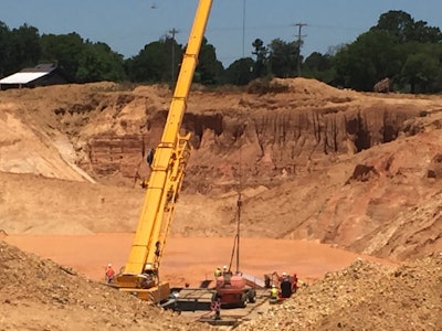 In this photo released by the Mississippi Emergency Management Agency, a new crane is used to assist in the recovery efforts to remove two workers buried under a landslide at the bottom of a pit at Green Brothers Gravel Co., in Crystal Springs, Miss., Tuesday, June 7, 2016. (Ray Coleman/Mississippi Emergency Management Agency via AP)