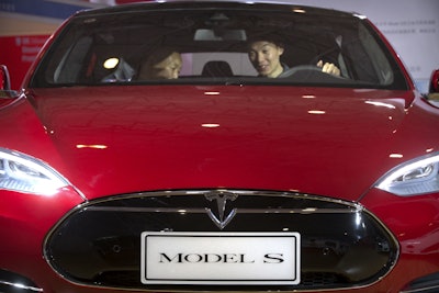 In this Monday, April 25, 2016, file photo, a man sits behind the steering wheel of a Tesla Model S electric car on display at the Beijing International Automotive Exhibition in Beijing. Tesla said Thursday, June 9, 2016, that it has started selling a cheaper version of its Model S car in an attempt to make its electric vehicles more affordable for more people. The new version, called the Model S 60, starts at $66,000. An all-wheel drive version of the Model S 60 will start at $71,000. Both cost less that the current Model S 90D, which starts at $89,500. (AP Photo/Mark Schiefelbein, File)