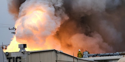 Los Angeles County Firefighters stand on top of a roof and watch as an explosion erupts from a factory in Maywood, Calif. on Tuesday, June 14, 2016. Explosions rocked a small Los Angeles County city early Tuesday as an inferno raged through a business containing metals and and firefighters decided to allow the blaze to burn itself out. (AP Photo/Richard Vogel)