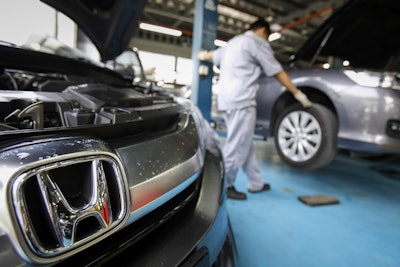 An automotive technician works on a Honda car at a service centre in Kuala Lumpur, Malaysia, Monday, June 27, 2016. A Malaysian woman has died after the airbag in her Honda City ruptured in a minor collision, a safety official said Monday. (AP Photo/Joshua Paul)