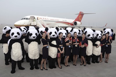 People in panda costumes pose with air stewardess in front of a Chengdu Airlines ARJ21-700 plane before its first commercial flight at Chengdu Shuangliu International Airport in Chengdu in southwestern China's Sichuan Province Tuesday, June 28, 2016. The first regional jet produced in China's initiative to compete in the commercial aircraft market made its debut flight Tuesday carrying 70 passengers. The ARJ21-700 jet is one of a series of initiatives launched by the ruling Communist Party to transform China from the world's low-cost factory into a creator of profitable technology in aviation, clean energy and other fields. (Chinatopix Via AP)