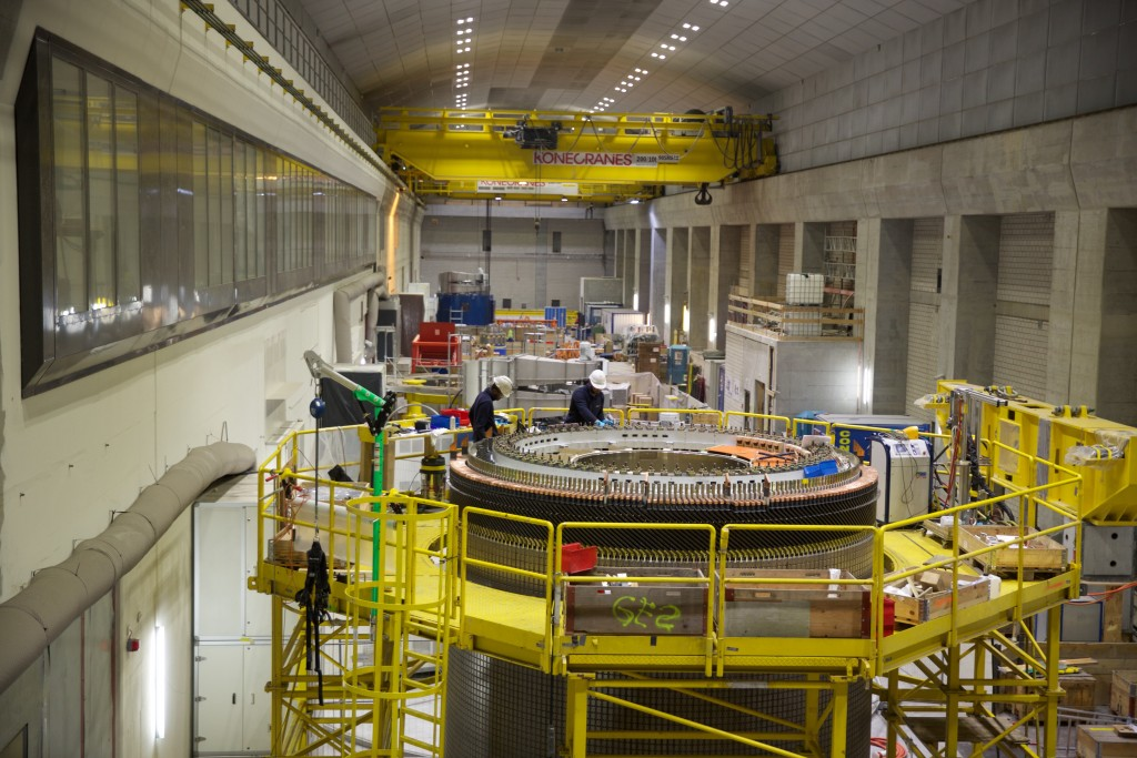 The generator hall deep inside the mountain. In the front, workers are assembling the rotor for one of the pump turbines. Since it’s too large to transport through the network of tunnels, workers must assemble some equipment on-site. (Image credit: GE Reports/Tomas Kellner)