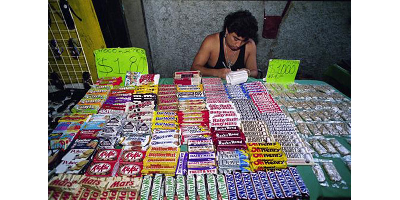 FILE - In this Nov. 16, 1993, file photo, a street vendor sells chocolates in Mexico City. A study published Tuesday, July 5, 2016, shows that Mexico's 8-percent tax on high-calorie snacks has been successful in reducing junk food purchases, but only by a small amount and only among poor and middle-class households. (AP Photo/Damian Dovarganes, File)