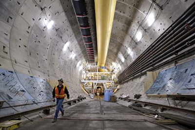 In this photo taken April 25, 2016, a worker walks inside the State Route 99 tunnel under construction in Seattle. The troubled project to replace Seattle's Alaskan Way Viaduct is $223 million over budget, the Washington state Department of Transportation said Thursday, July 21, 2016. The original completion date for the tunnel was the fall of 2015, but the latest estimate for the opening of the double-decker highway project is in 2018. (AP Photo/Elaine Thompson, File)