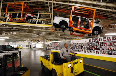 Vehicles are suspended above other installation stations as they are moved along the assembly line at the Nissan Canton Vehicle Assembly Plant in Canton, Miss. (AP Photo/Rogelio V. Solis)