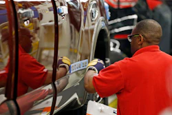 A technician applies the logo stencil to the side of a Titan truck on the assembly line at the Nissan Canton Vehicle Assembly Plant in Canton, Miss. (AP Photo/Rogelio V. Solis)