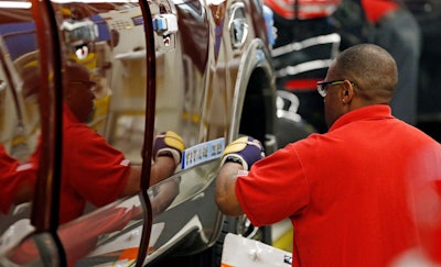 A technician applies the logo stencil to the side of a Titan truck on the assembly line at the Nissan Canton Vehicle Assembly Plant in Canton, Miss. (AP Photo/Rogelio V. Solis)