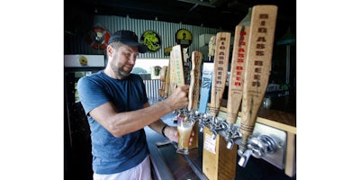 In this July 12, 2016 photo, Joe Winiarski owner of a small farm and brewery in Wildwood, Fla. pours a beer from one of the many selections that his brewery offers. Winiarski is recognized as the first commercial hops grower in Florida. (AP Photo/John Raoux)