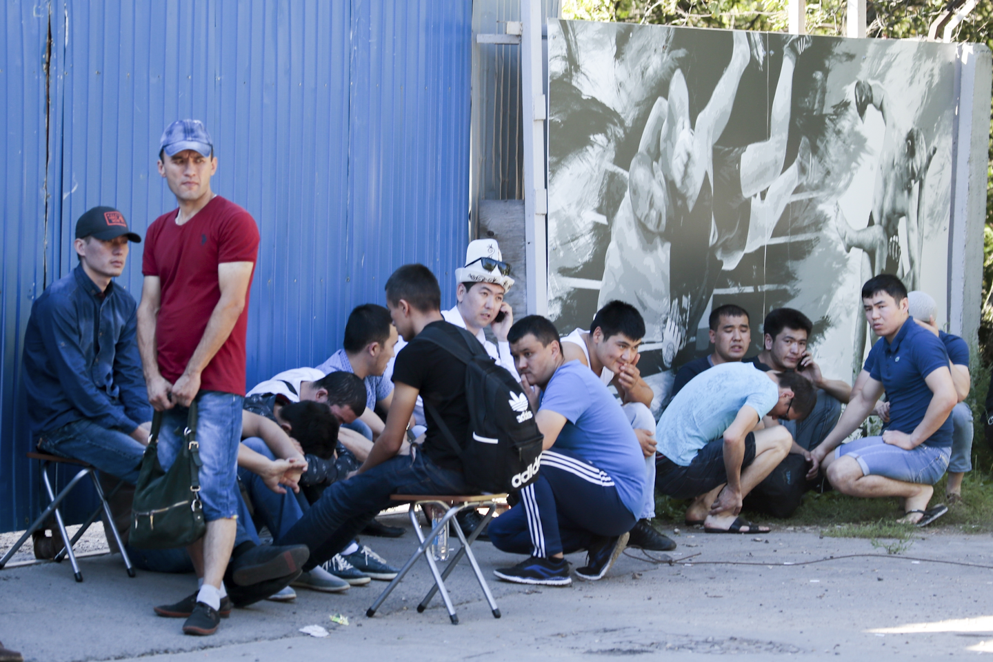 Colleagues and relatives of dead workers from Kyrgyzstan react as they gather next to the burnt building of a printing plant's warehouse in Moscow, Russia, Saturday, Aug. 27, 2016. Russian emergency services say a fire swept through a printing plant's warehouse in Moscow on Saturday, killing 17 migrant workers from Kyrgyzstan. (AP Photo/Ivan Sekretarev)