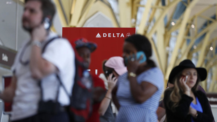 Travelers talk on their cell phones as they stand in line at the Delta ticketing counter at Washington's Ronald Reagan Washington National Airport, Monday, Aug. 8, 2016. (AP Photo/Carolyn Kaster)